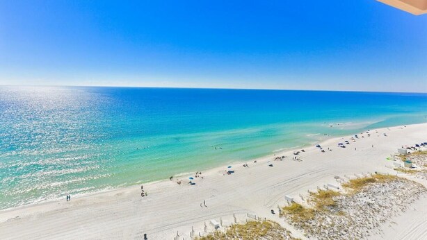 A beach with clear turquoise water, white sand, and a few people walking. - Destin Towers 143 (Destin)