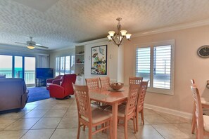 A dining area with a table and chairs, a ceiling fan, and a chandelier.