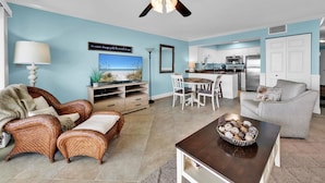 A living room with wicker furniture, a TV, and a ceiling fan.