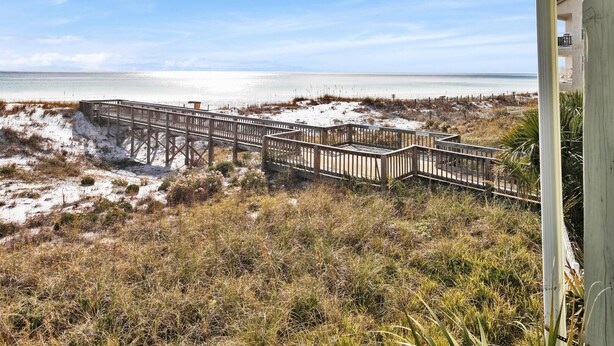 A wooden boardwalk leading to a beach with a clear view of the ocean.