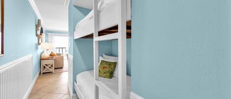 Un dormitorio con literas, una mesita de noche pequeña, una lámpara y vistas al balcón.