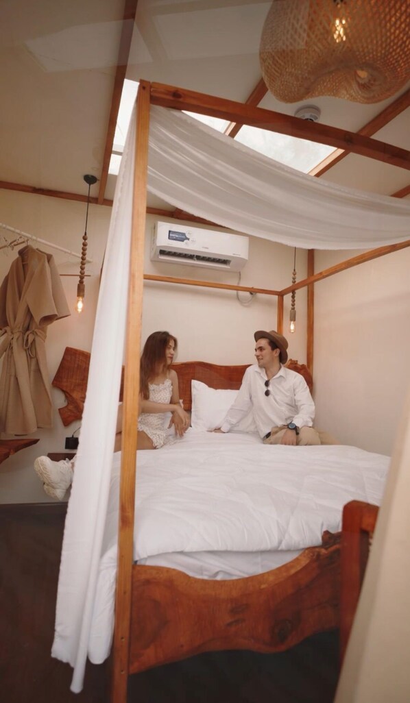 Relax in a serene bedroom with a comfortable bed, canopy, and air conditioning for a restful stay.