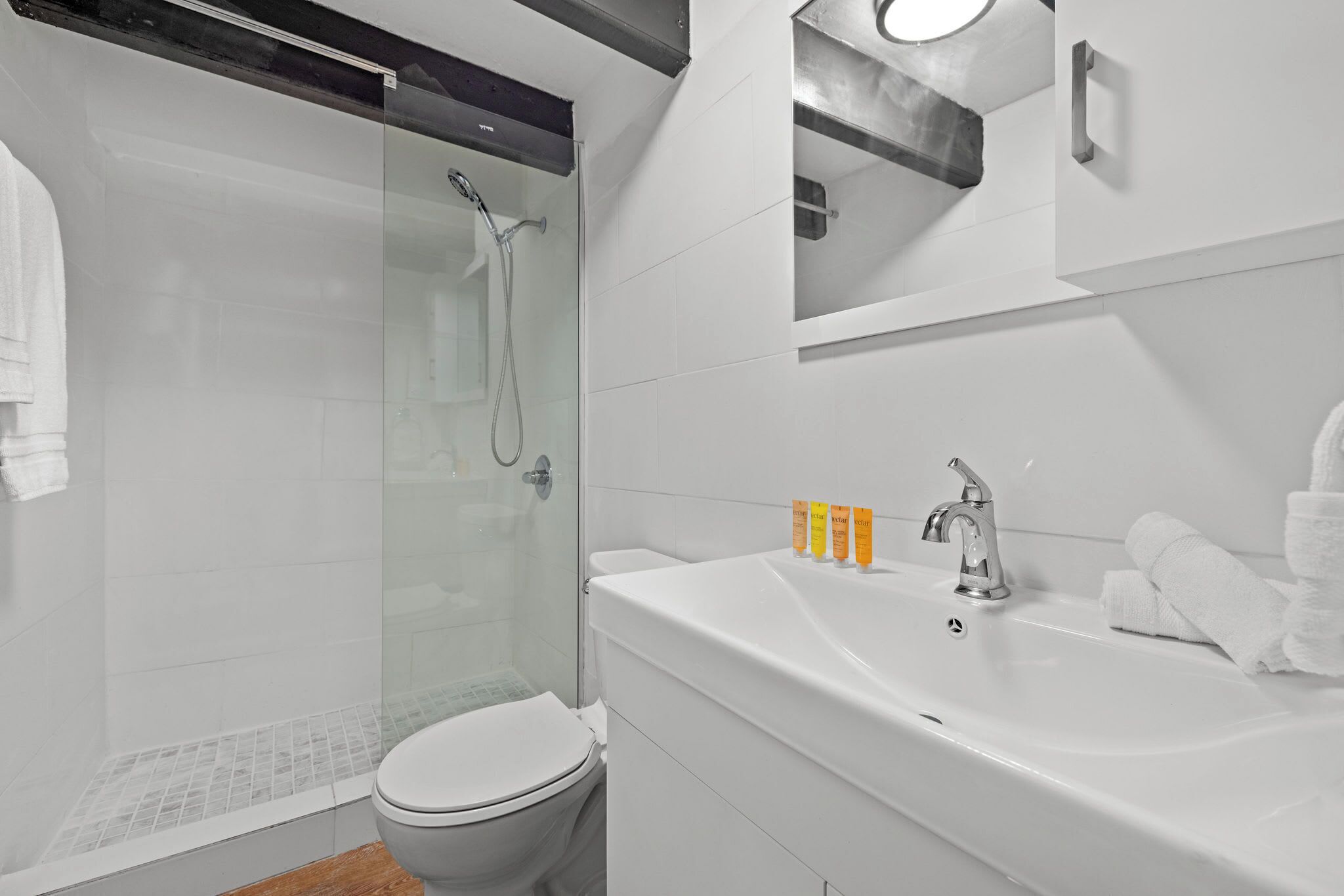 A modern bathroom with a glass-enclosed shower, a white sink, and a toilet.