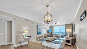 A dining area with a chandelier, a television, and a view of the ocean. - Destin on the Gulf 702 (Destin)