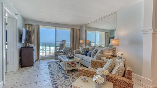 A spacious living room with a large window overlooking the ocean, a comfortable sofa set, a coffee table, and a television. - Destin on the Gulf 703 (Destin)