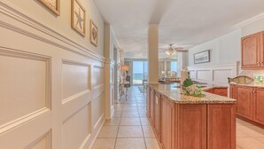 A spacious kitchen with a large island, wooden cabinets, and a view to the outside. - Destin on the Gulf 703 (Destin)