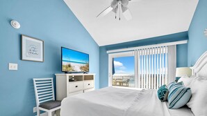 Une chambre à coucher comprenant un lit, une télévision, une chaise, un bureau et une fenêtre avec des stores.