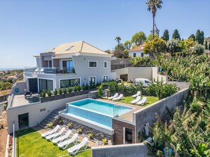 A modern two-story house with a swimming pool, sun loungers, and a view of the sea. - Sunshine Deluxe B by Madeira Sun Travel (Ponta do Sol)