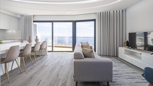 A modern living room with a sofa, TV, and dining area. - Sunshine Deluxe B by Madeira Sun Travel (Ponta do Sol)