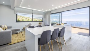 A modern kitchen with a central island, large windows, and a view of the sea. - Sunshine Deluxe C by Madeira Sun Travel (Ponta do Sol)