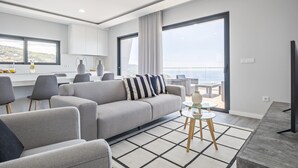 A modern living room with a sofa, chairs, a coffee table, and a view of the sea. - Sunshine Deluxe D by Madeira Sun Travel (Ponta do Sol)