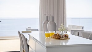 A modern dining area with a view of the sea, featuring a white table with two glasses of orange juice, a croissant, and a small vase with flowers. - Sunshine Deluxe D by Madeira Sun Travel (Ponta do Sol)