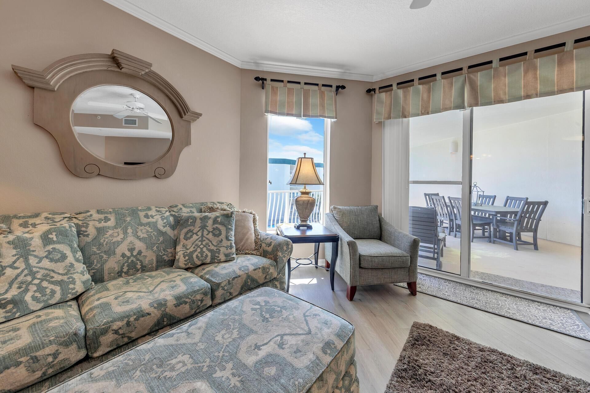 Una sala de estar con sofá, sillón y una mesa con lámpara. Cuenta con un balcón que ofrece vistas al cielo y barandilla.