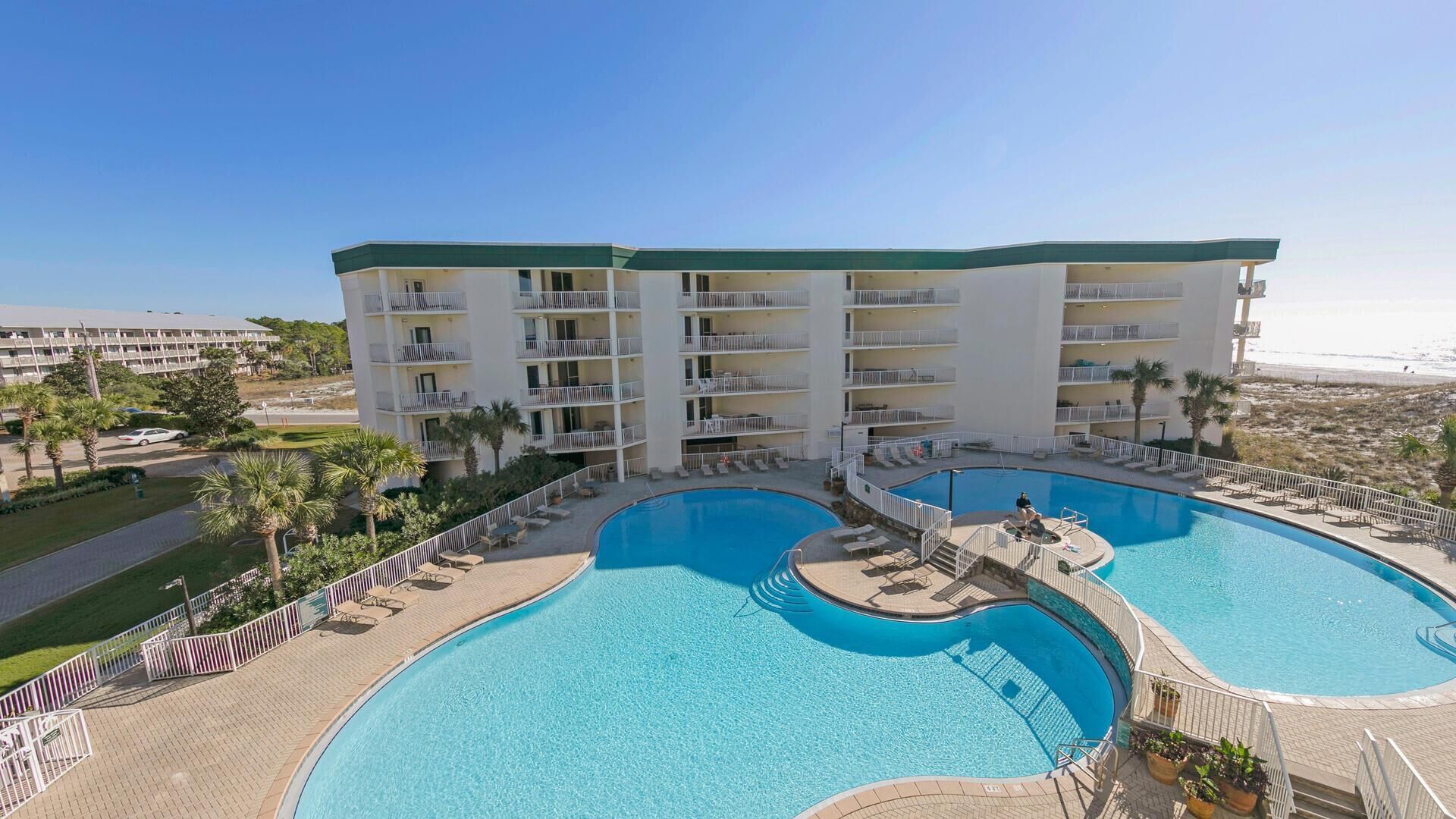 Un hôtel doté de nombreux balcons, d’une piscine centrale et offrant une vue sur la plage.