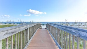 Une promenade en bois qui mène à une plage, avec un ciel dégagé.
