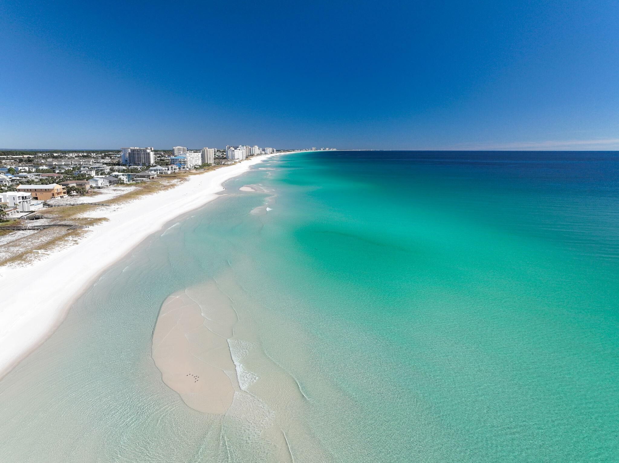 A coastal cityscape with a wide sandy beach and a clear blue ocean.