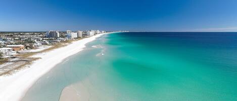A coastal cityscape with a wide sandy beach and a clear blue ocean.