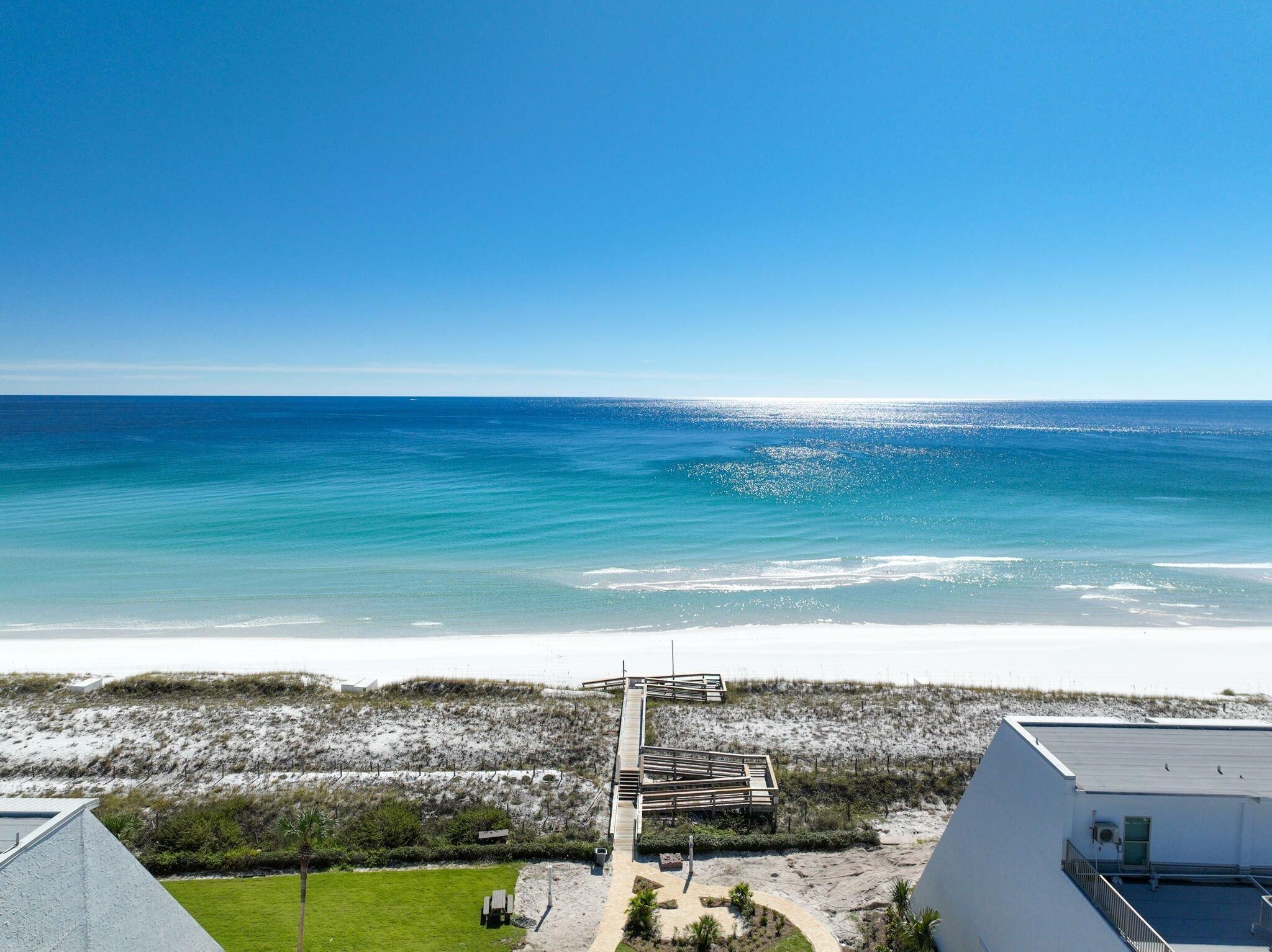 A coastal view with a sandy beach and a clear blue sky.