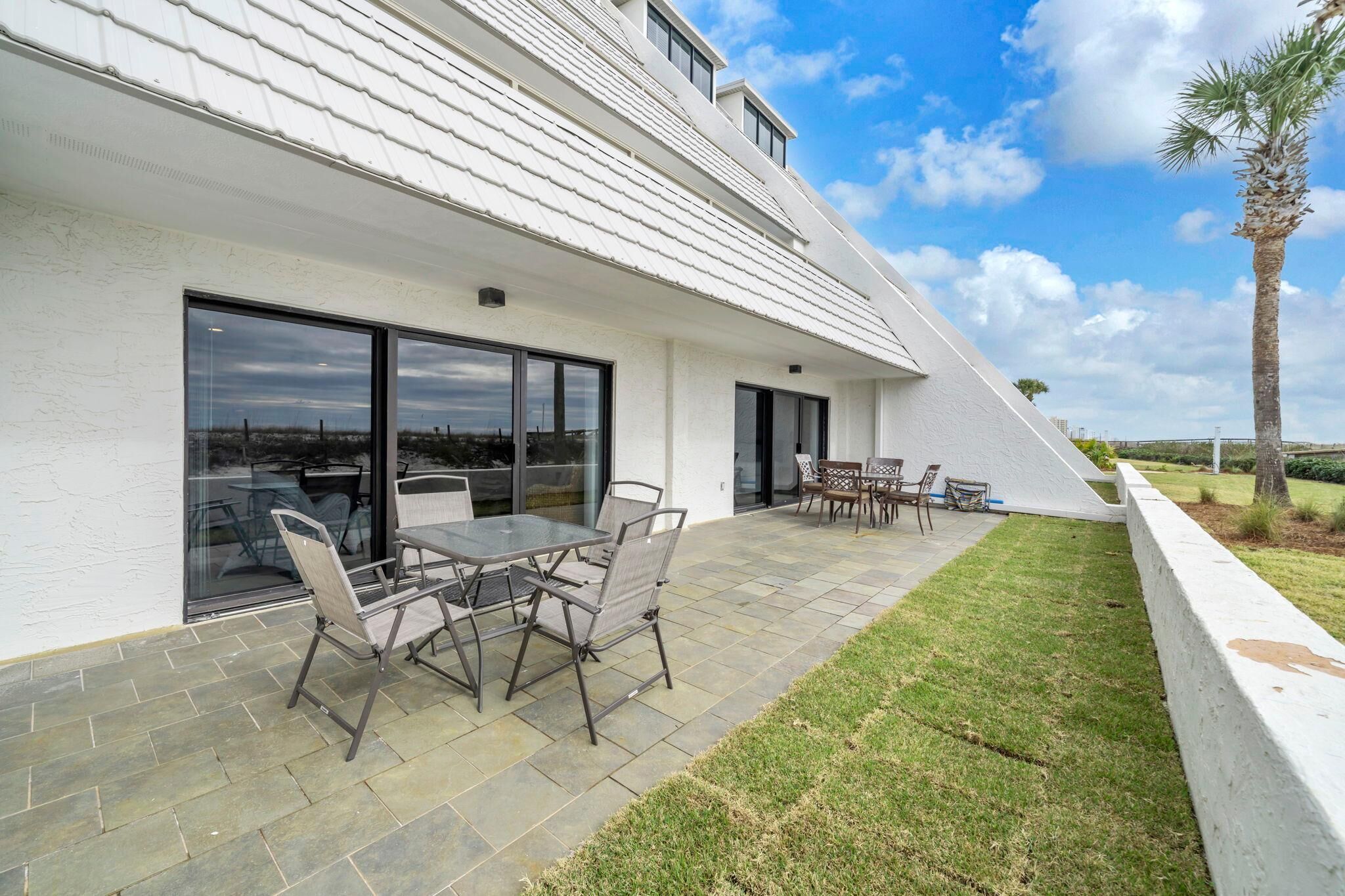 A modern house with a patio area featuring a table and chairs, a white exterior, and a view of the landscape.