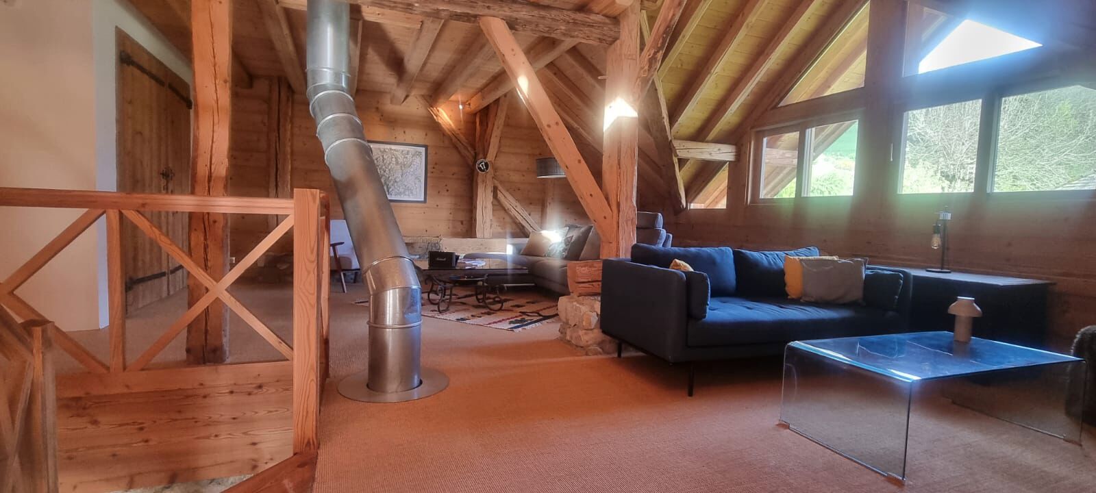 A rustic wooden interior with a sofa, a clear glass coffee table, and a stone fireplace.