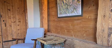 Una habitación acogedora con una mesa de piedra, una silla de mimbre y una cama con almohadas.