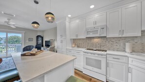 Una cocina moderna con armarios blancos, una isla central, un microondas y una estufa.