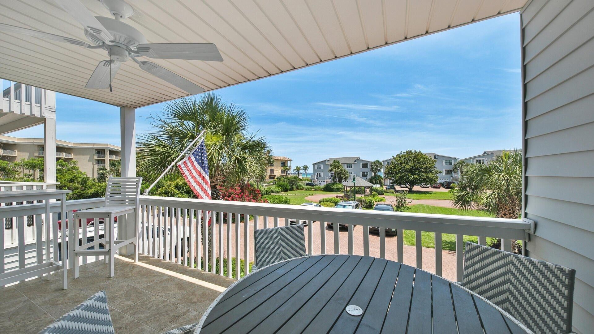 A covered outdoor area with a table and chairs, a flag, and a view of a residential complex.