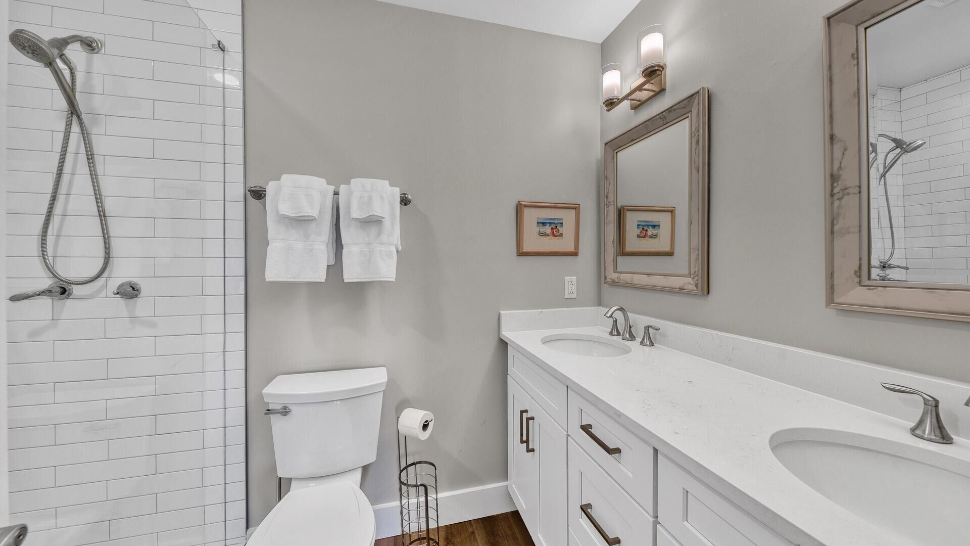 A modern bathroom with a shower, toilet, and vanity with a sink and mirror.