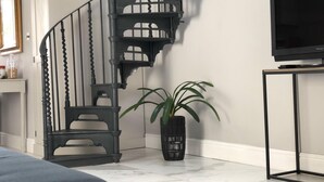 A spiral staircase with a black metal finish, a potted plant, and a television on a stand. - Wimbledon - Apartment - Sleeps 2 -private Entrance (London)