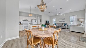 A spacious living area with a dining table, chairs, a television, and a sofa. - Beach Bum Hideaway (Santa Rosa Beach)