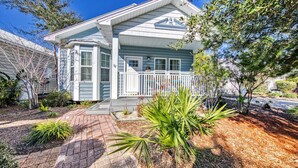 A two-story house with a covered porch, number 82, surrounded by landscaped garden beds and mature trees. - Beach Bum Hideaway (Santa Rosa Beach)