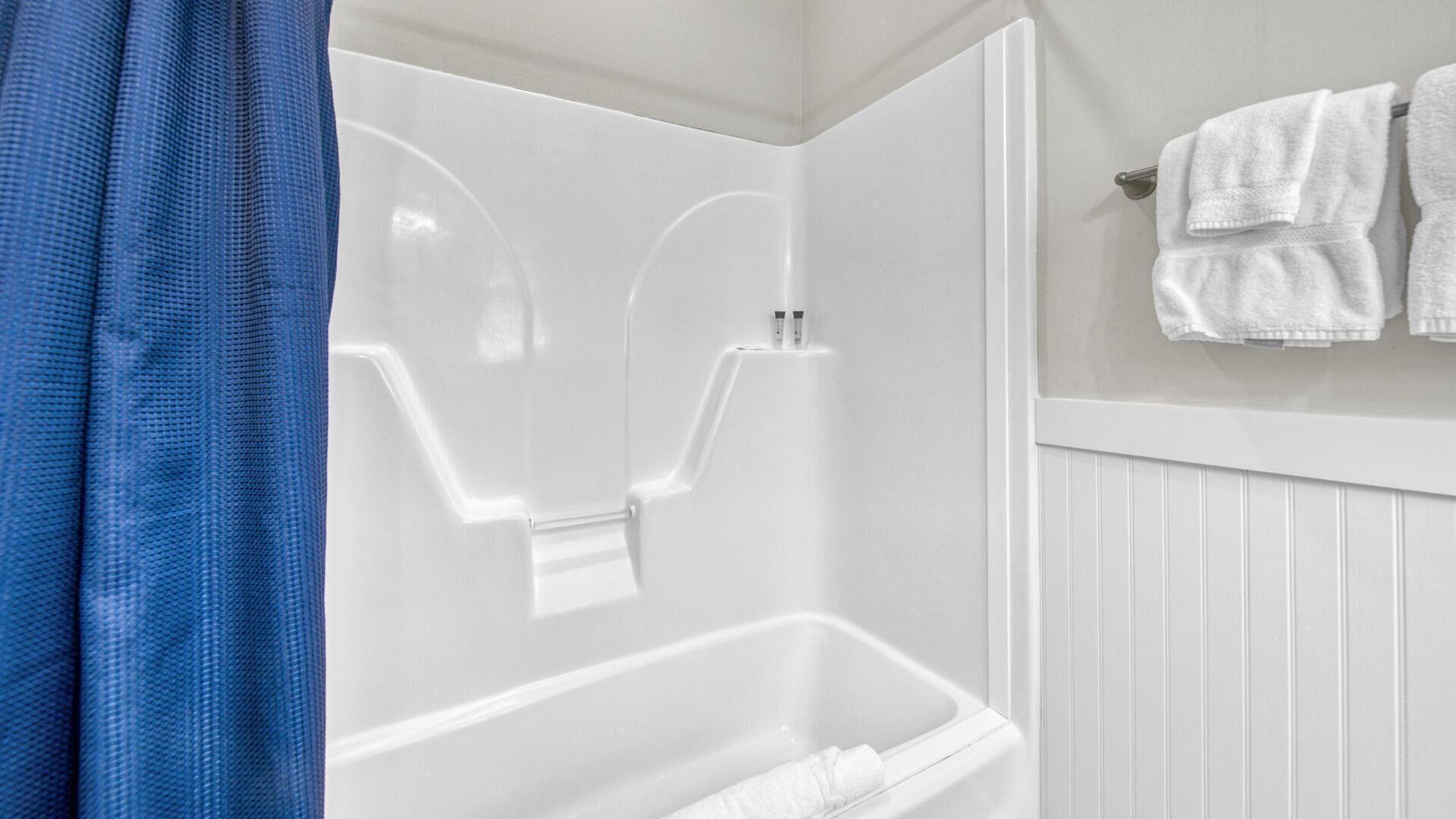 Une salle de bain avec une baignoire blanche, un espace douche et un porte-serviettes avec des serviettes.