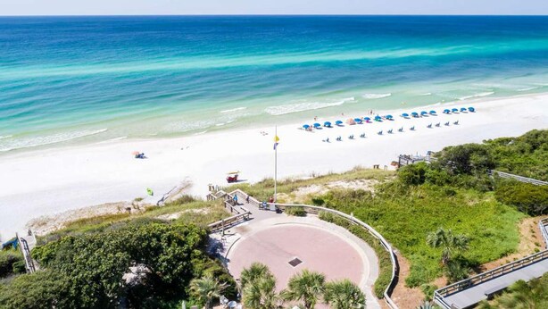A beach with clear turquoise waters, a white sandy shore, and a paved walkway leading to the beach. - Beach Bum Hideaway (Santa Rosa Beach)