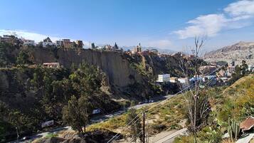 Un paisaje montañoso con una carretera, edificios y vegetación escasa.