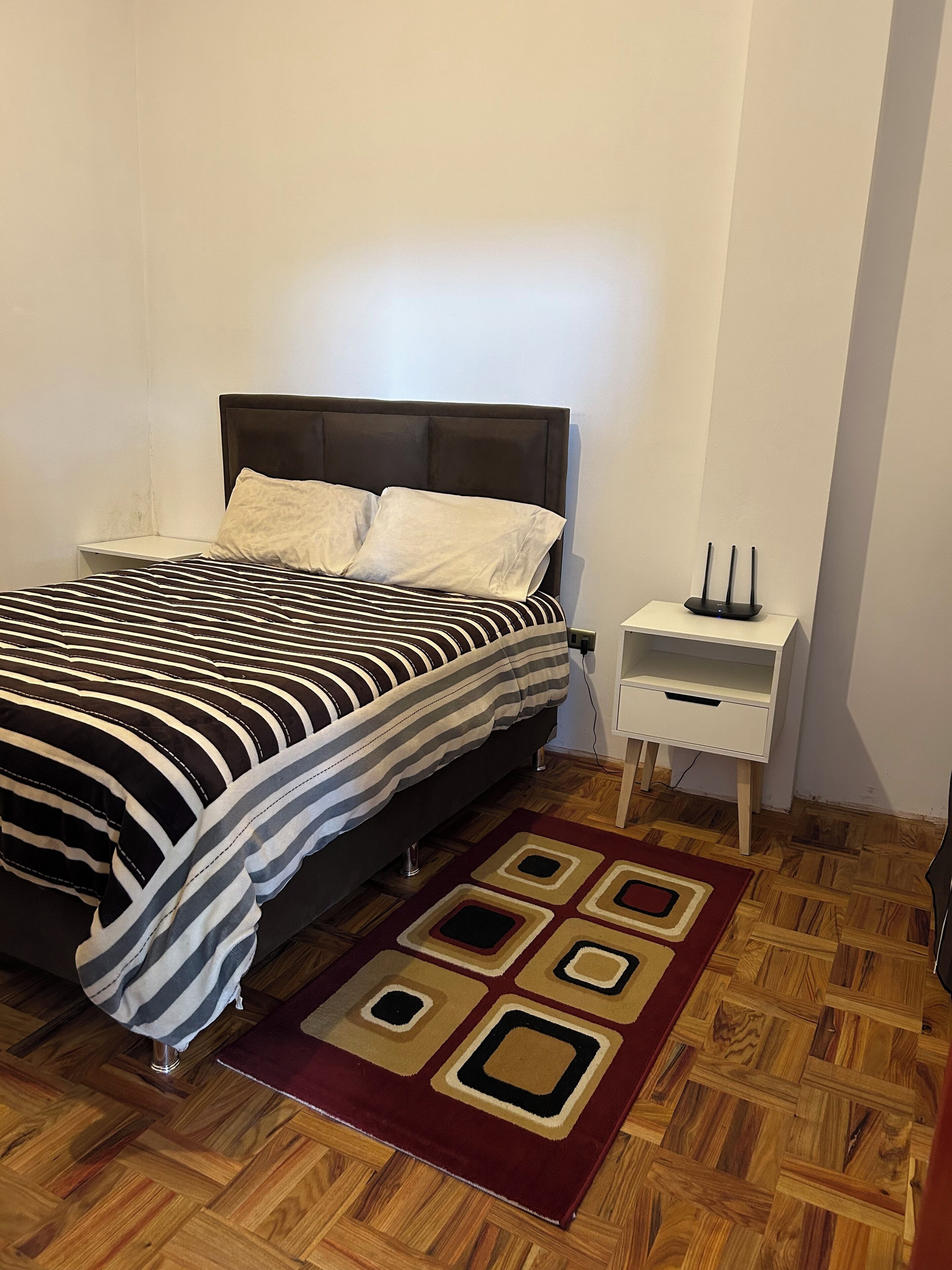 Ein Schlafzimmer mit einem Bett, einem Nachttisch und einem an der Wand befestigten Ladegerät.