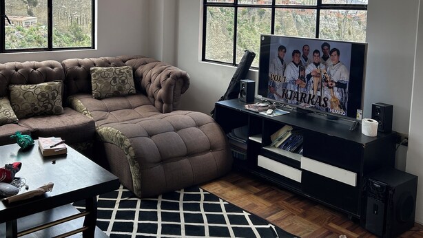 Una sala de estar con un ventanal grande, un sofá, un televisor y una mesa de centro.