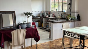Una cocina amplia con comedor, piso de madera y un gran ventanal que proporciona luz natural.