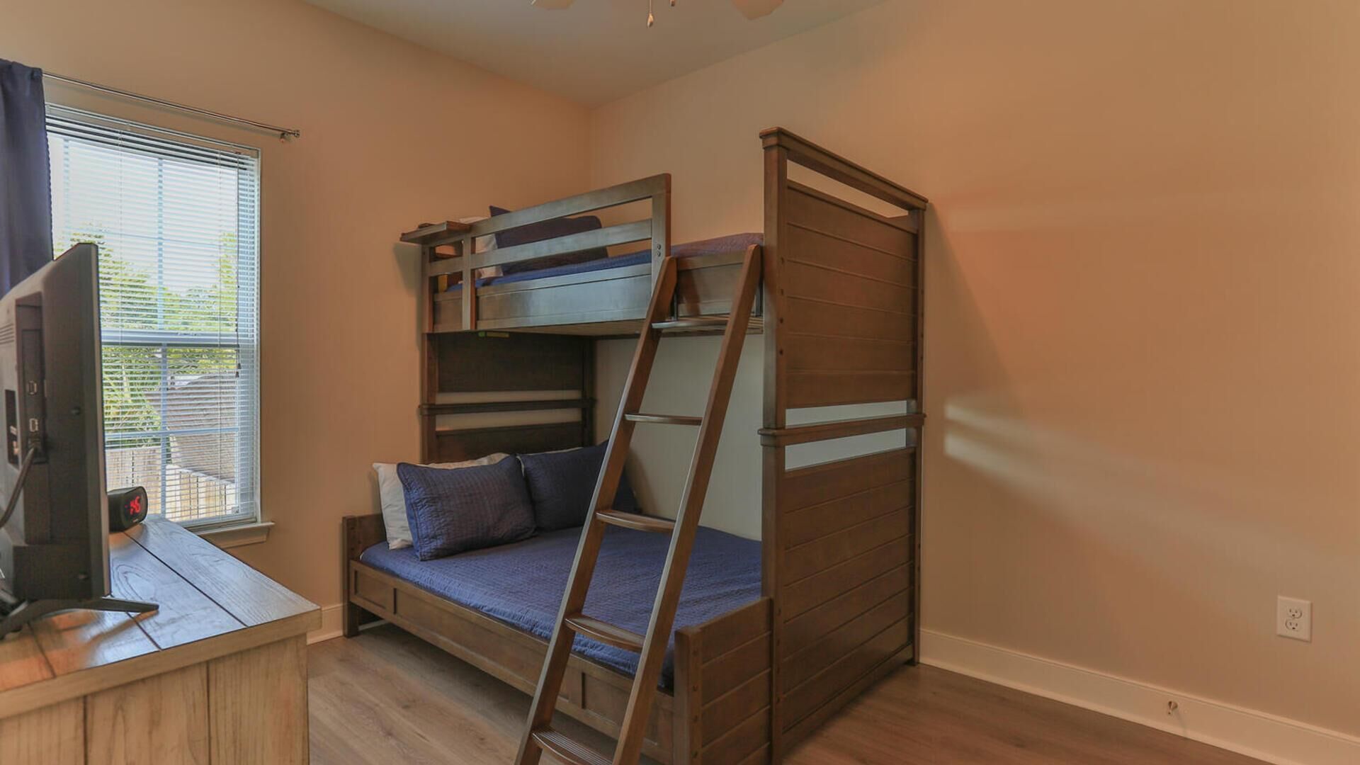 A bunk bed room with a desk and a ladder.