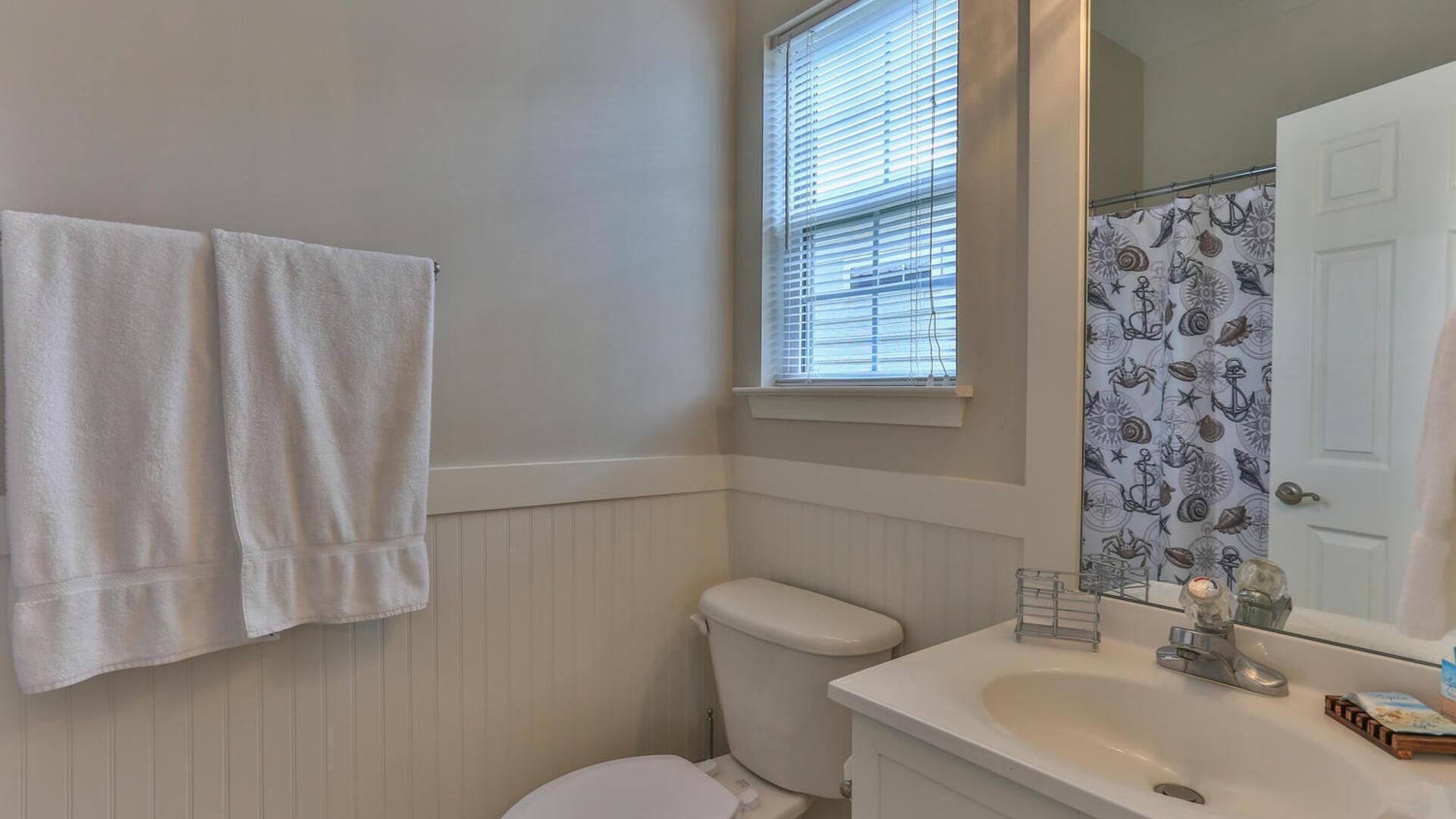 A bathroom with a toilet, sink, and window with blinds.