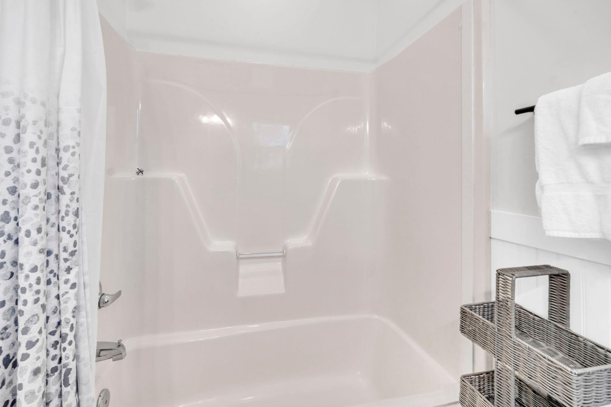 A bathroom with a bathtub, a shower curtain, and a towel rack.