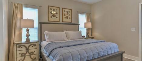A bedroom with a bed, two nightstands, a headboard, and two wall-mounted lamps.