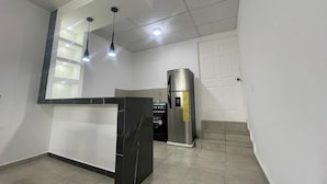 A kitchen with a black marble island, stainless steel refrigerator, and pendant lights. - Apartamento Nuevo, Moderno, Acogedor y muy Accesible a Todo en San Salvador (Mejicanos)