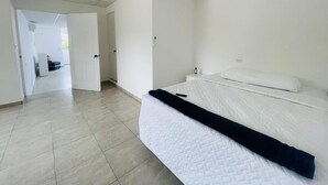 A room with a bed, a white wall, and a tiled floor. - Apartamento Nuevo, Moderno, Acogedor y muy Accesible a Todo en San Salvador (Mejicanos)