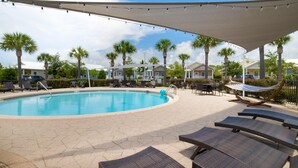 A pool area with lounge chairs, a hammock, and palm trees. - Kk's Beach House (Santa Rosa Beach)