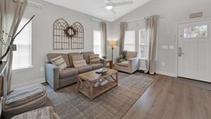 A spacious living room with a sofa set, a coffee table, and a decorative wall piece. - Kk's Beach House (Santa Rosa Beach)