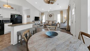 A modern kitchen with white cabinets, a black refrigerator, and a granite countertop. - Kk's Beach House (Santa Rosa Beach)
