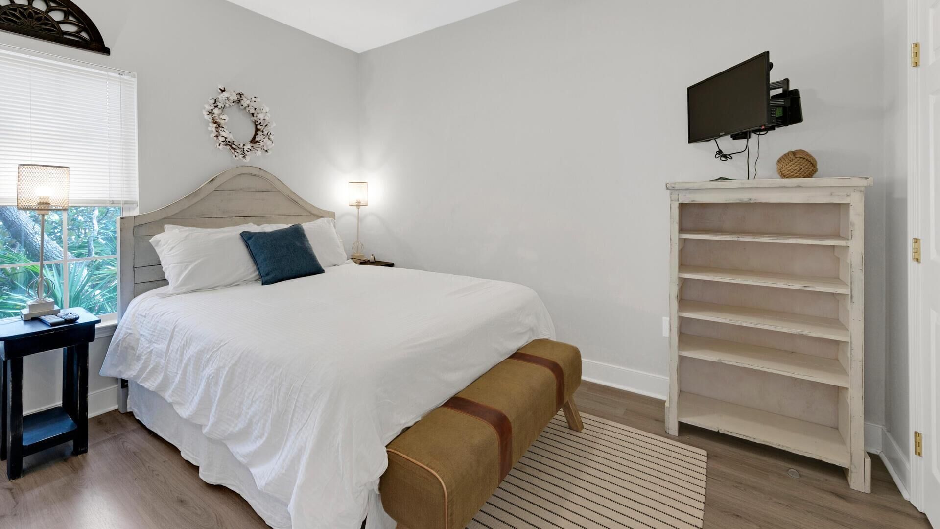 Une chambre à coucher avec un lit, des tables de chevet, une télévision et une armoire blanche.