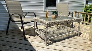 A deck with wicker furniture, a glass table, and a bottle of lotion. - Family-sized home 5 minutes from beaches & Point Pelee National Park! (Leamington)