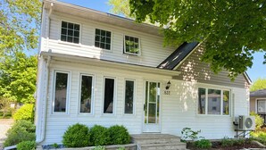 A two-story house with a front porch, a number 837 sign, and a small garden with stepping stones. - Family-sized home 5 minutes from beaches & Point Pelee National Park! (Leamington)