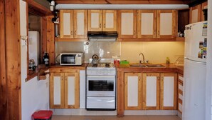 Une cuisine de taille réduite, dotée de meubles en bois, d’un four à micro-ondes, d’une cuisinière et d’un évier.